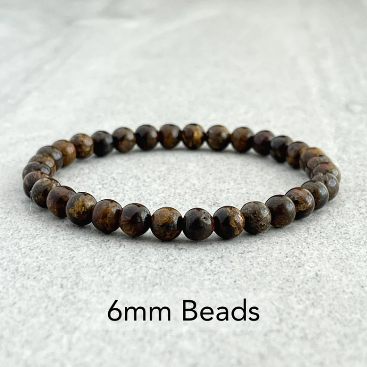 Natural bronzite stone beads bracelet with 6mm beads on a gray surface.